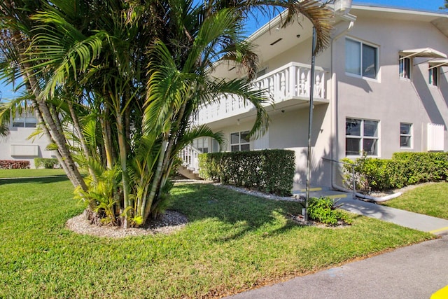 view of home's exterior featuring a lawn and a balcony