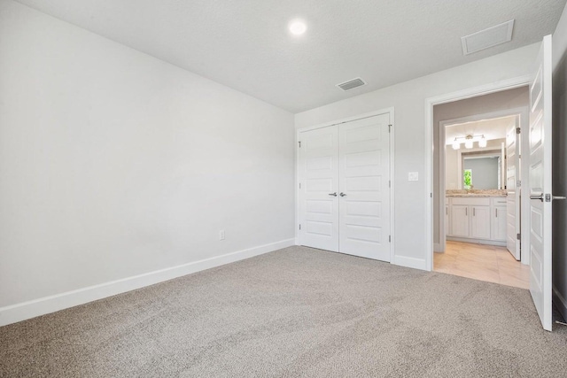 unfurnished bedroom featuring light carpet, a textured ceiling, and a closet