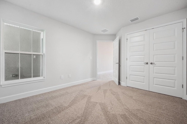 unfurnished bedroom featuring a closet, carpet floors, and a textured ceiling