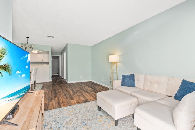 living room featuring a chandelier and dark wood-type flooring