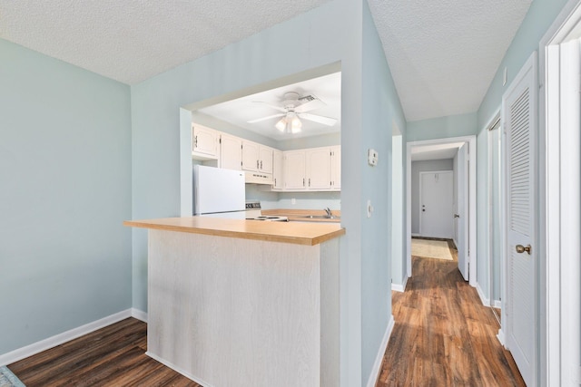 kitchen featuring kitchen peninsula, dark hardwood / wood-style flooring, white cabinets, white fridge, and range with electric stovetop