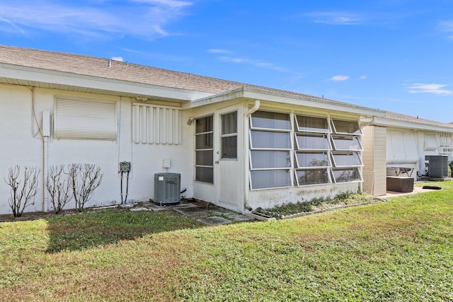 view of side of home with central AC and a lawn