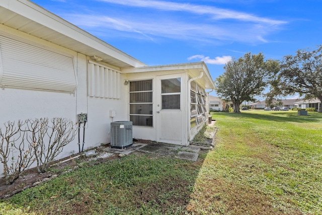 view of side of home featuring central AC unit and a lawn