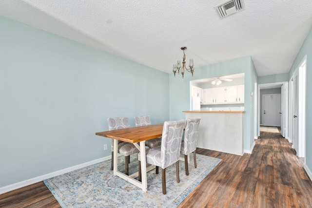 dining space featuring dark wood-type flooring, a textured ceiling, and a notable chandelier