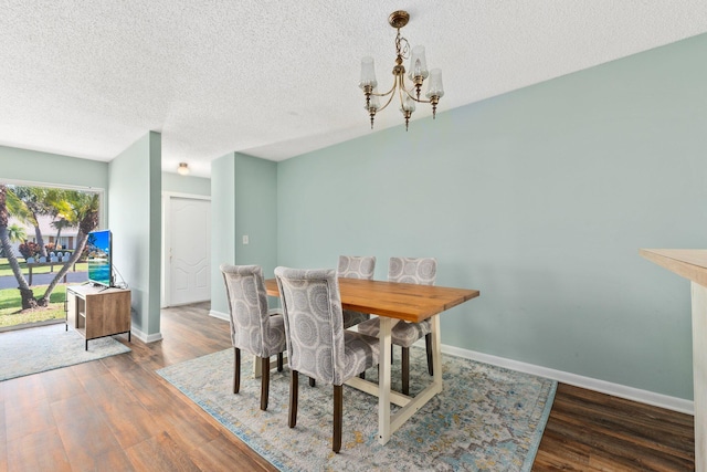 dining space featuring a textured ceiling, dark wood-type flooring, and a notable chandelier