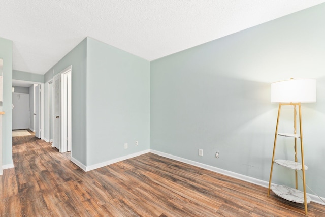 unfurnished room featuring dark hardwood / wood-style flooring and a textured ceiling