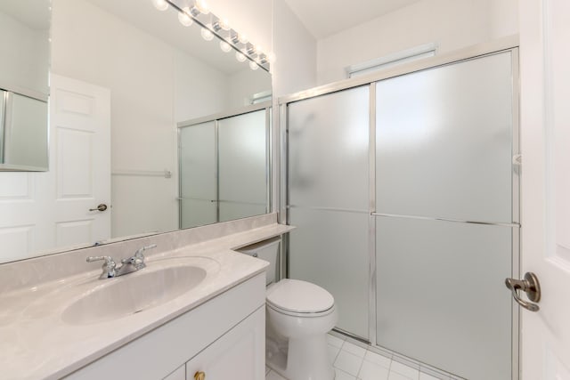 bathroom featuring tile patterned flooring, vanity, toilet, and a shower with door