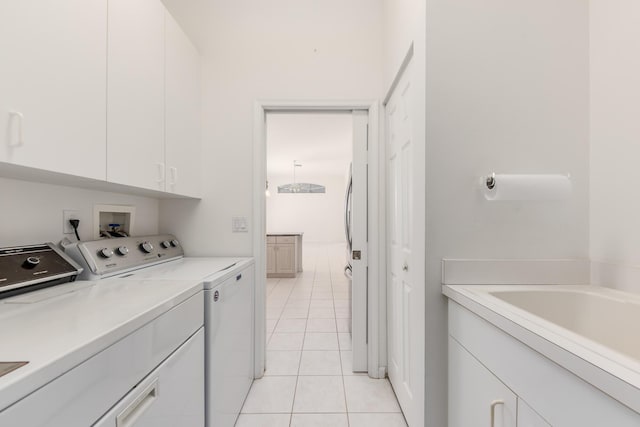 laundry room with cabinets, light tile patterned floors, and washing machine and clothes dryer