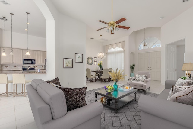 tiled living room with ceiling fan with notable chandelier and a towering ceiling