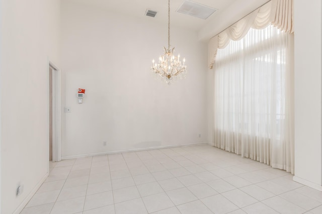 tiled spare room featuring a notable chandelier