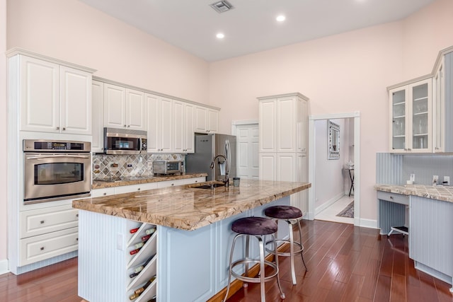 kitchen featuring appliances with stainless steel finishes, sink, white cabinets, dark hardwood / wood-style floors, and an island with sink