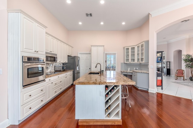 kitchen featuring hardwood / wood-style floors, a center island with sink, white cabinets, sink, and stainless steel appliances