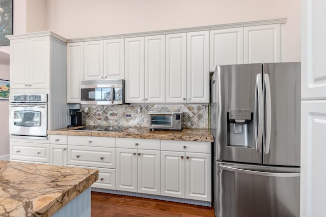 kitchen with dark hardwood / wood-style floors, decorative backsplash, white cabinetry, and appliances with stainless steel finishes