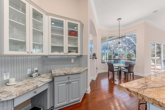 kitchen featuring light stone countertops, pendant lighting, dark hardwood / wood-style floors, and ornamental molding