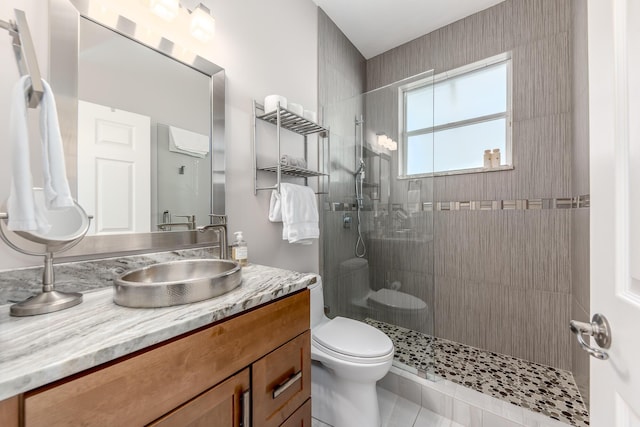 bathroom with tile patterned floors, vanity, toilet, and a tile shower