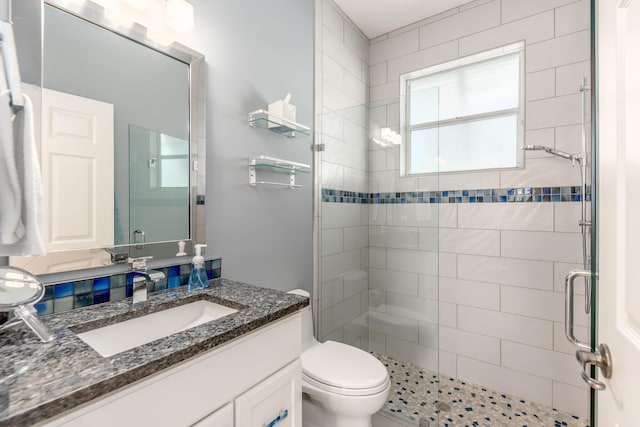 bathroom featuring vanity, toilet, and a shower with shower door