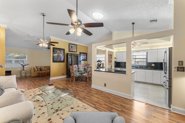 living room featuring light hardwood / wood-style flooring, ceiling fan, lofted ceiling, and crown molding