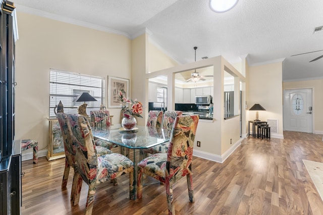 dining space with ceiling fan, ornamental molding, a textured ceiling, and hardwood / wood-style flooring