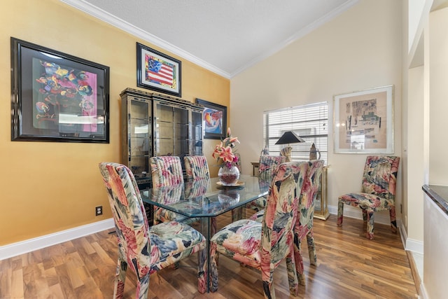 dining space featuring hardwood / wood-style floors, vaulted ceiling, and crown molding