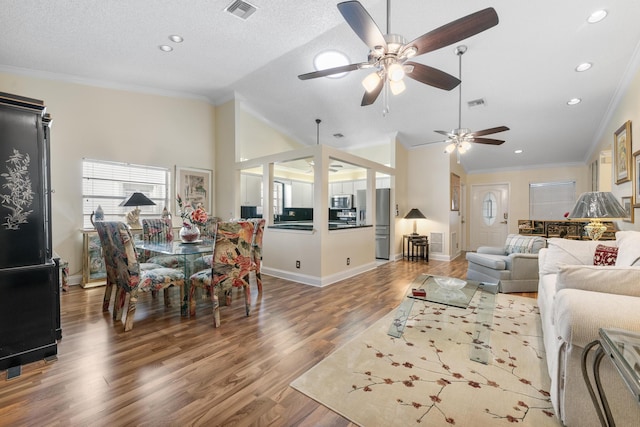 living room with a textured ceiling, vaulted ceiling, ceiling fan, crown molding, and hardwood / wood-style flooring