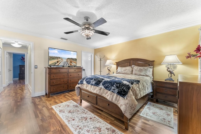 bedroom featuring ceiling fan, wood-type flooring, a textured ceiling, and ornamental molding