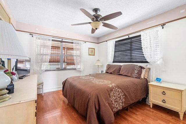 bedroom with ceiling fan, wood-type flooring, and a textured ceiling