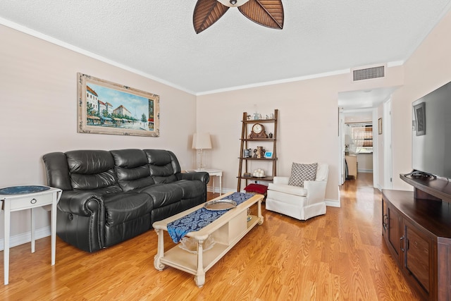 living room featuring a textured ceiling, light hardwood / wood-style flooring, ceiling fan, and crown molding