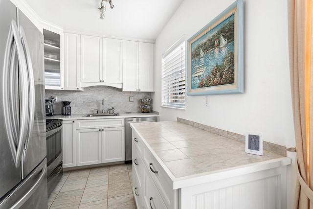 kitchen featuring sink, light tile patterned floors, tasteful backsplash, white cabinetry, and stainless steel appliances