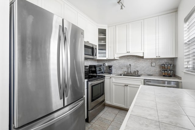 kitchen featuring sink, backsplash, tile countertops, white cabinets, and appliances with stainless steel finishes