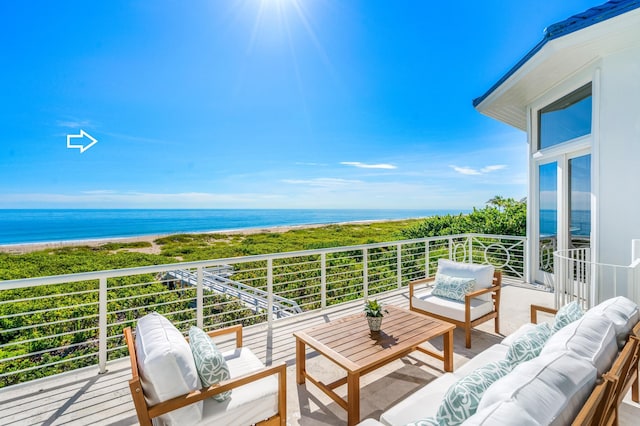 balcony with an outdoor living space, a water view, and a beach view