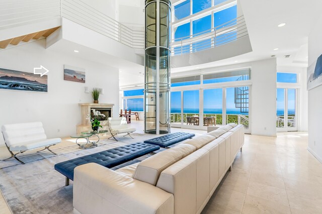 tiled living room featuring a water view and a high ceiling