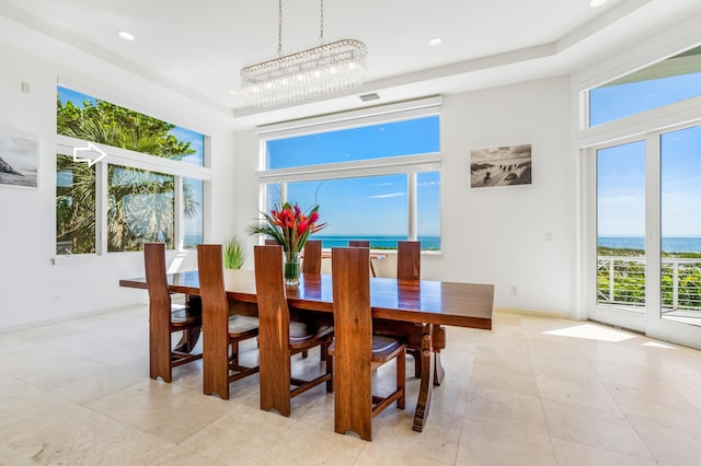 dining area with a water view, a healthy amount of sunlight, light tile patterned floors, and a notable chandelier