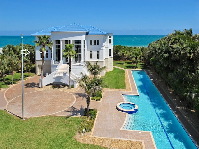 view of swimming pool with an in ground hot tub, a water view, a patio area, and a lawn