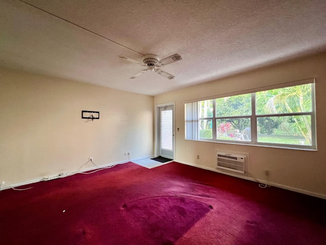 carpeted spare room with an AC wall unit, ceiling fan, and a textured ceiling