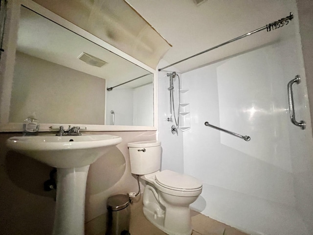 bathroom with tile patterned flooring, toilet, and a shower