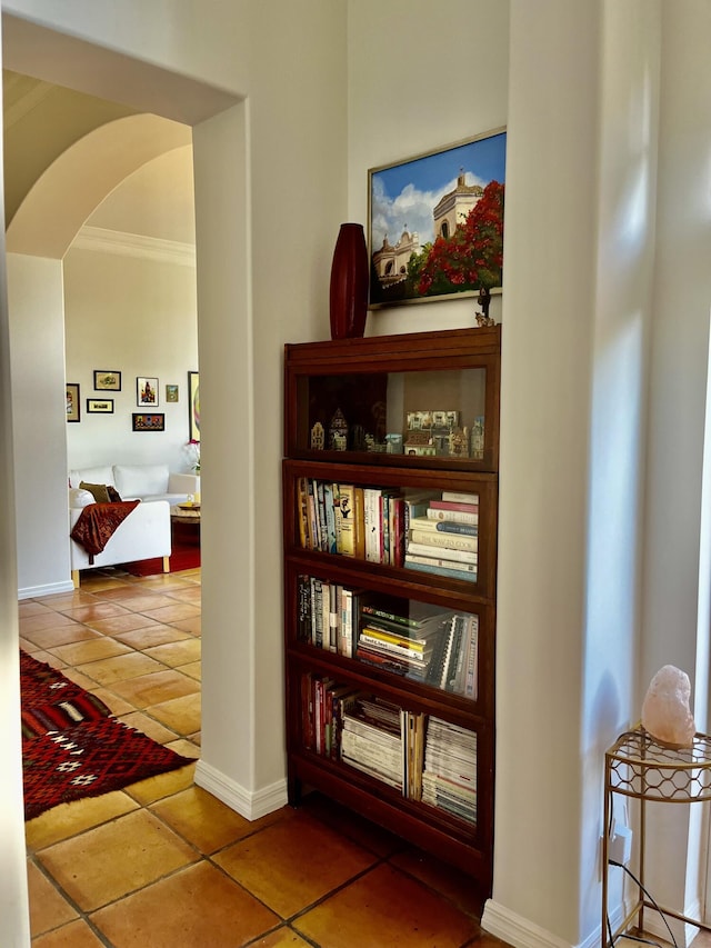 corridor with tile patterned floors and crown molding