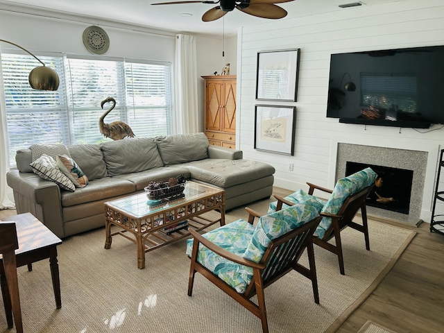 living room with hardwood / wood-style flooring, ceiling fan, and wood walls