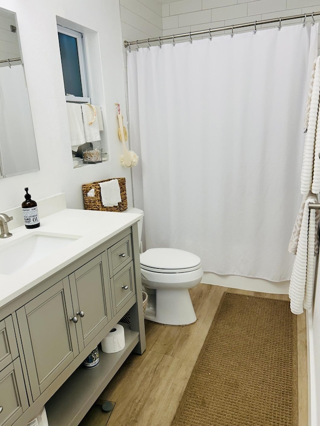 bathroom with a shower with curtain, vanity, toilet, and wood-type flooring