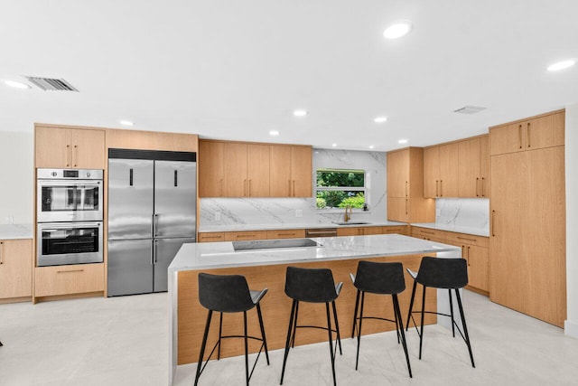 4246 Live Oak Blvd, Delray Beach, FL 33445 - kitchen featuring stainless steel appliances, decorative backsplash, a kitchen breakfast bar, recessed lighting, and light brown cabinetry