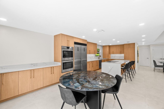4246 Live Oak Blvd, Delray Beach, FL 33445 - kitchen with black appliances, a breakfast bar, a kitchen island, light stone countertops, and backsplash