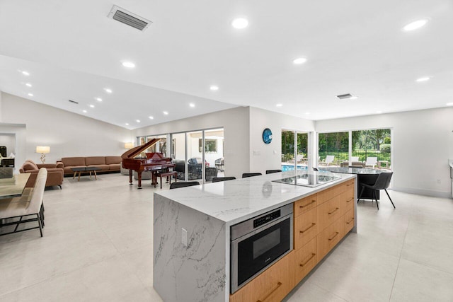 4246 Live Oak Blvd, Delray Beach, FL 33445 - kitchen featuring modern cabinets, black electric stovetop, a large island, light brown cabinetry, and light stone counters