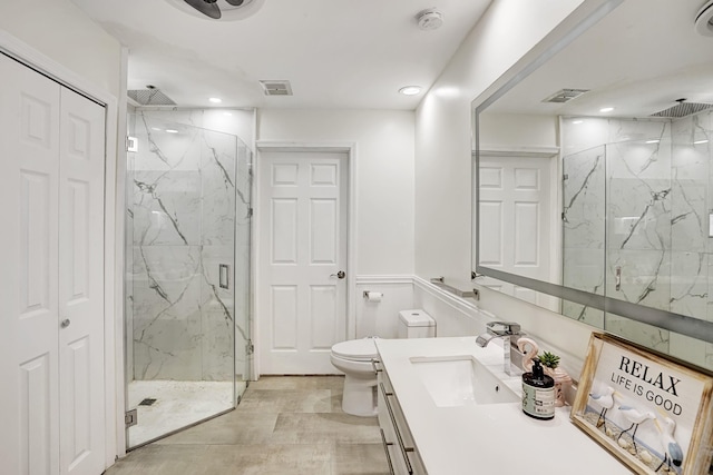 bathroom featuring vanity, a shower with shower door, and toilet