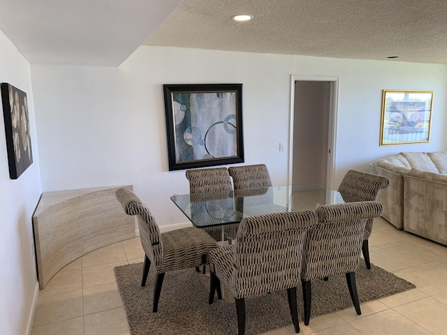 tiled dining space featuring a textured ceiling