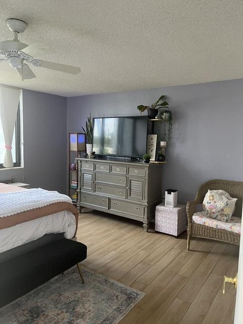 bedroom with ceiling fan, light hardwood / wood-style floors, and a textured ceiling