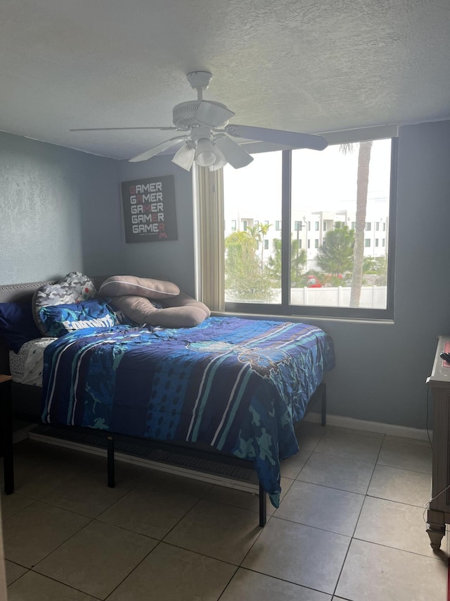 tiled bedroom featuring ceiling fan and a textured ceiling