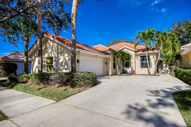 mediterranean / spanish house with a garage, concrete driveway, a tiled roof, fence, and stucco siding