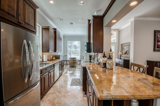 kitchen with light stone counters, a breakfast bar, stainless steel appliances, and ornamental molding