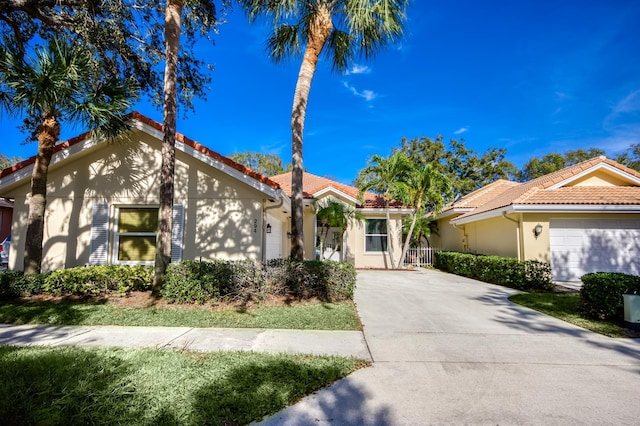 mediterranean / spanish house with a tiled roof, concrete driveway, an attached garage, and stucco siding