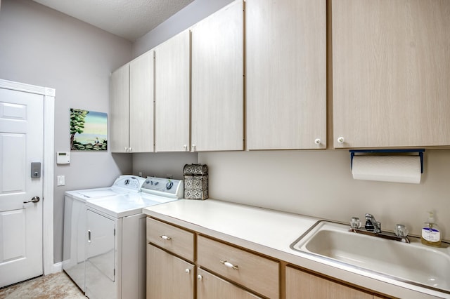 laundry area featuring washing machine and dryer, sink, and cabinets