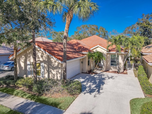 mediterranean / spanish-style house featuring a garage, stucco siding, fence, and a tiled roof